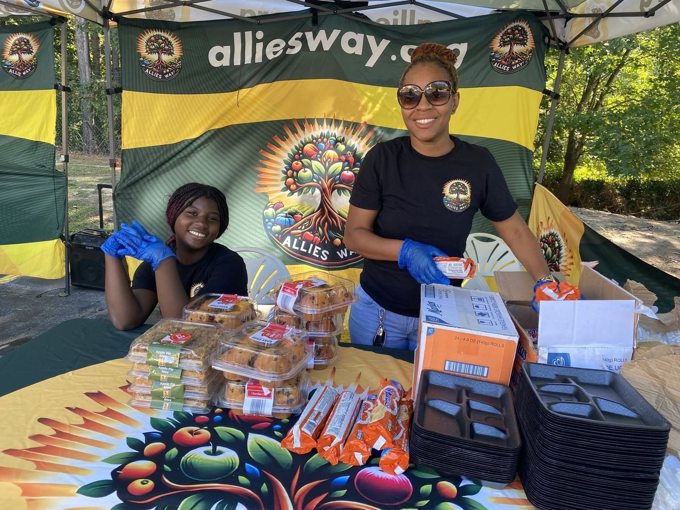 Allies Way volunteers smiling at a community meal tent